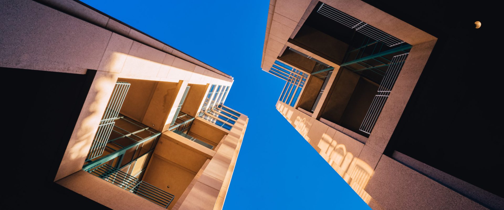 A frog's eye view of architectural twin buildings against a clear blue sky