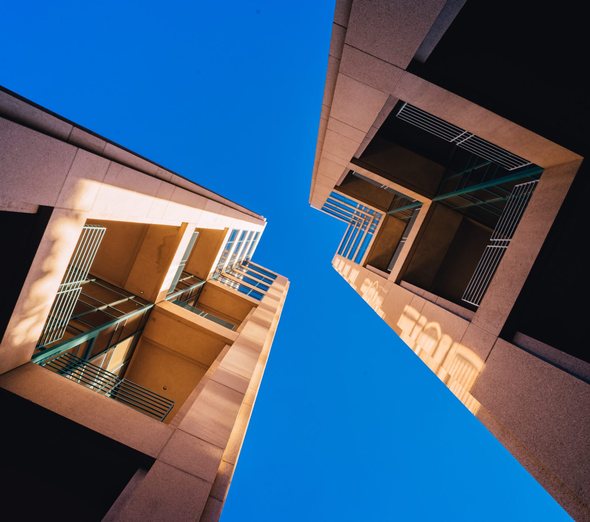 A frog's eye view of architectural twin buildings against a clear blue sky